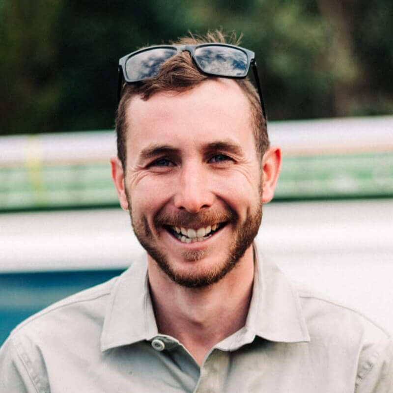 A smiling man wearing sunglasses in front of a van.